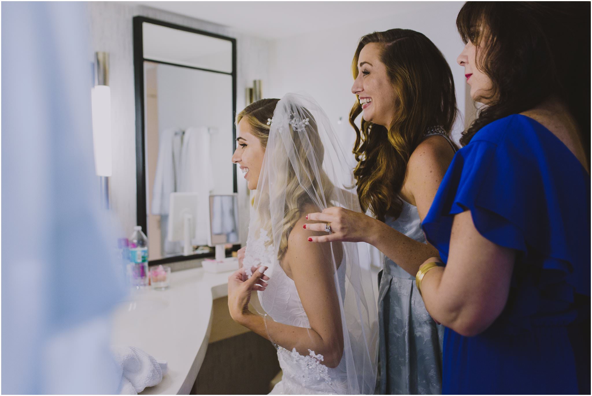 bride putting on her sister veil with mother