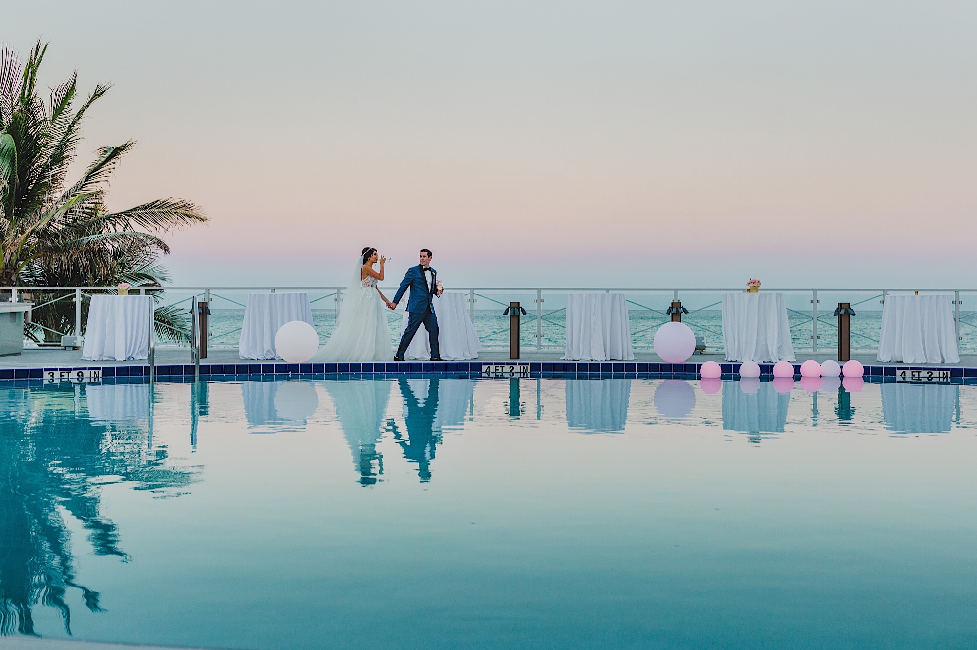 Couple walking along the Eden Roc pool during sunset